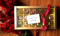 Gold-toned chocolate gift box with assorted truffles wrapped in satin ribbon