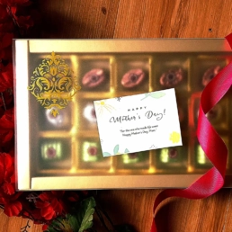 Gold-toned chocolate gift box with assorted truffles wrapped in satin ribbon